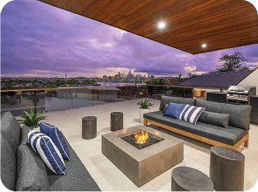 Modern rooftop outdoor living space with comfortable couches, firepit, and city skyline view, perfect for hosting and relaxation, with stylish design and scenic background.