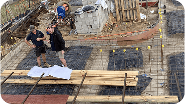 Construction site with workers planning and discussing the foundation; image representing building construction and project management.