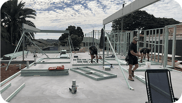 Construction workers building a modern website creator related structure on a rooftop with metal framework and tools in view.