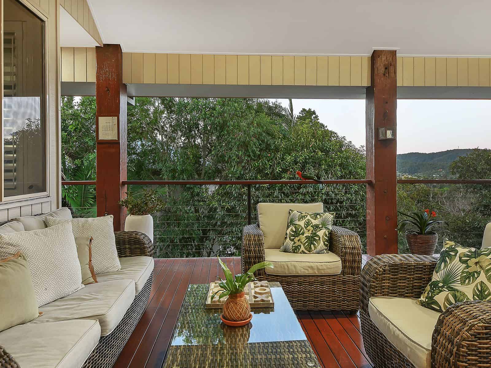 Balcony outdoor seating area with wicker furniture and lush greenery, perfect for relaxing and enjoying scenic views - Website Creator.