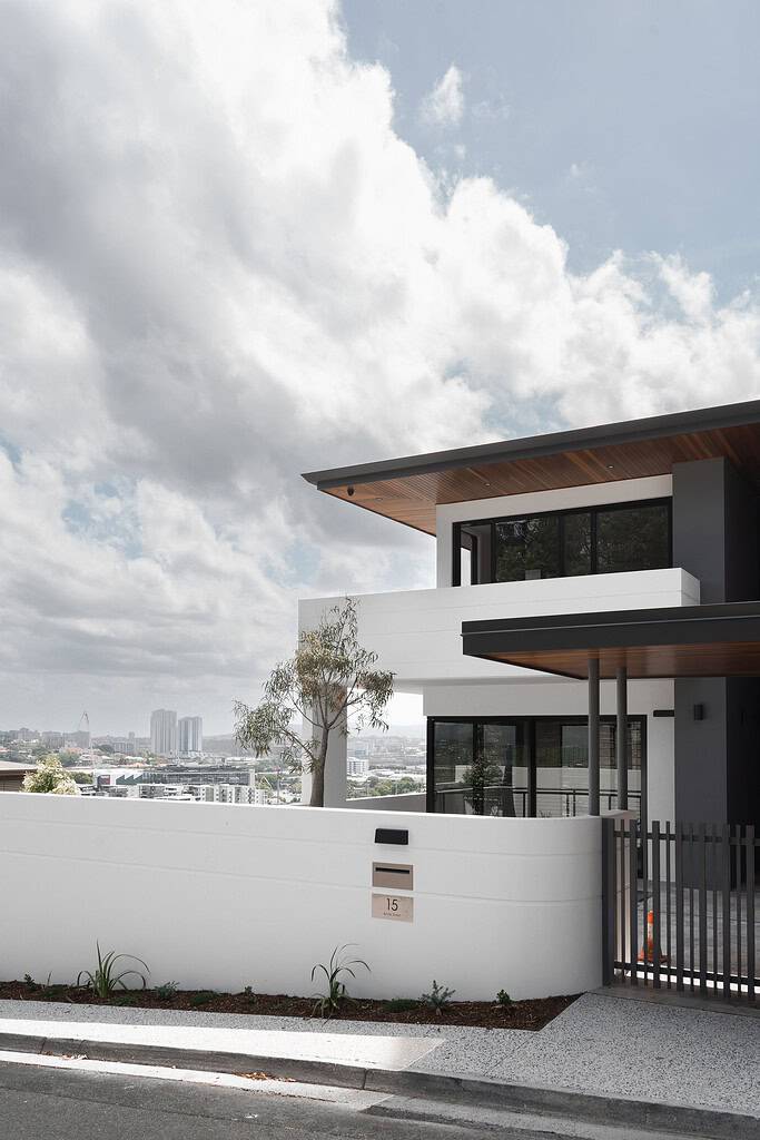 Modern minimalist house with clean lines, white walls, large glass windows, and wooden accents, showcasing contemporary architectural design in an urban setting.