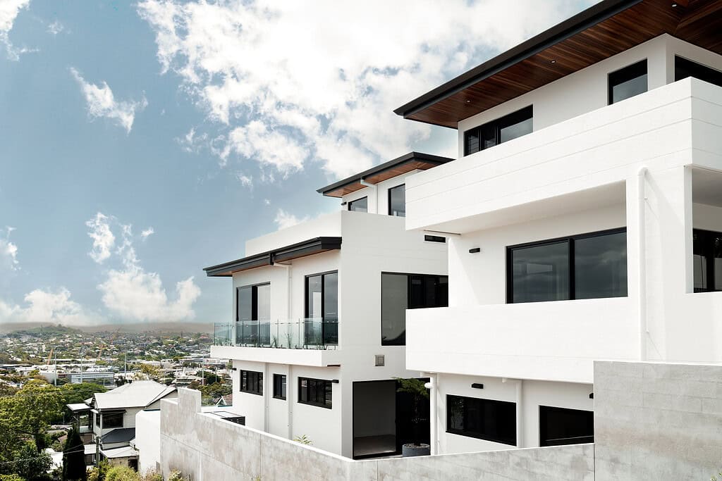 Modern white multi-storey residential building with large windows and glass balconies, showcasing contemporary architecture and innovative design for a stylish urban home.