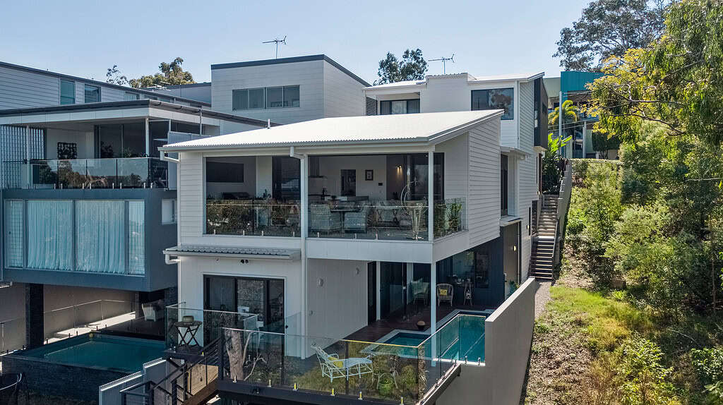 Modern multi-level house with outdoor pool, spacious balcony, and sleek design, showcasing contemporary architecture and lush green surroundings in an upscale neighbourhood.