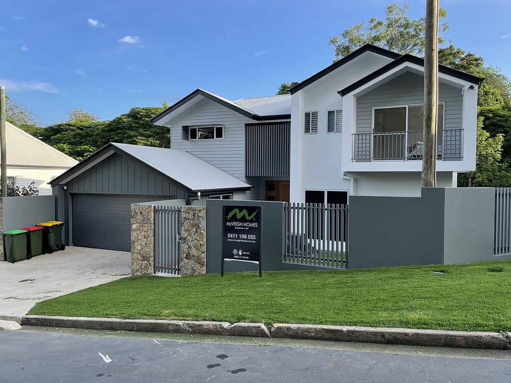 Modern two-storey custom-built home with contemporary design, grey and white exterior, spacious balcony, and landscaped front yard showcasing McVeigh Homes' quality construction.