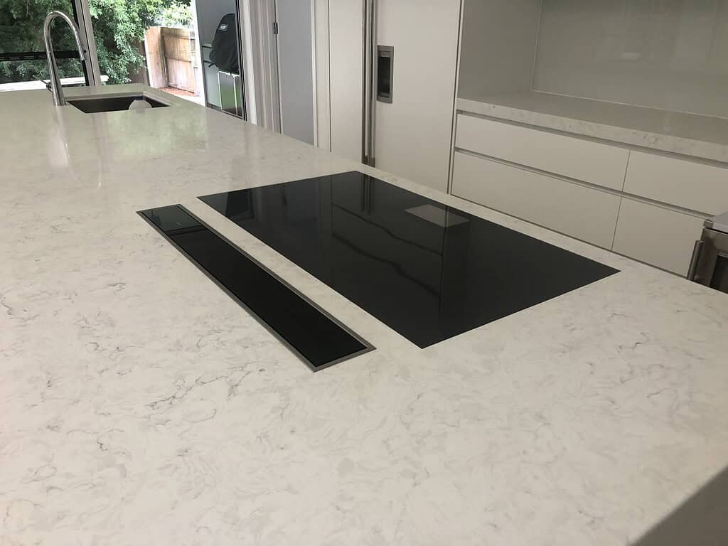 Sleek black induction cooktop installed on a luxurious white marble kitchen island countertop.
